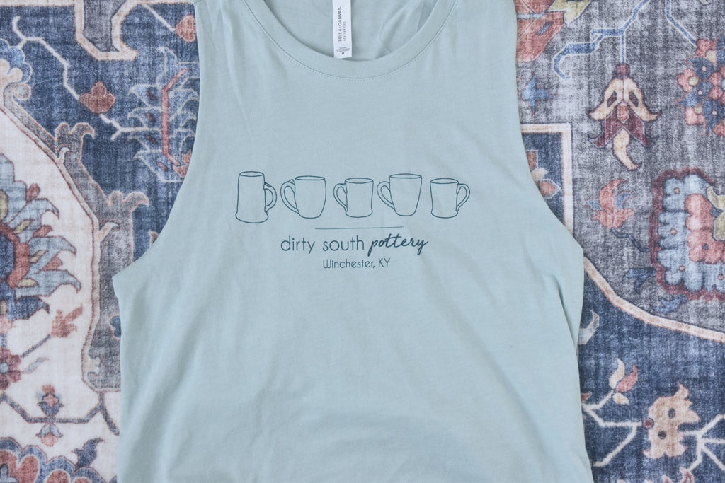 Pale Blue Women's Tank with row of illustrated mugs on it, with "Dirty South Pottery, Winchester, KY" written underneath. Design & photos copyright Dirty South Pottery, LLC 2024