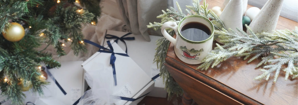 Sleigh Mug filled with coffee sits near a Christmas tree surrounded with handmade gifts