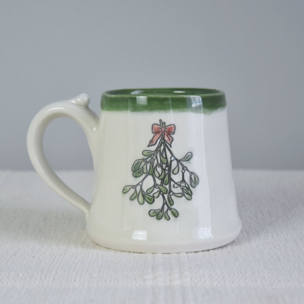 Handmade ceramic Christmas Mug with classic Mistletoe design, red bow, and green rim. 