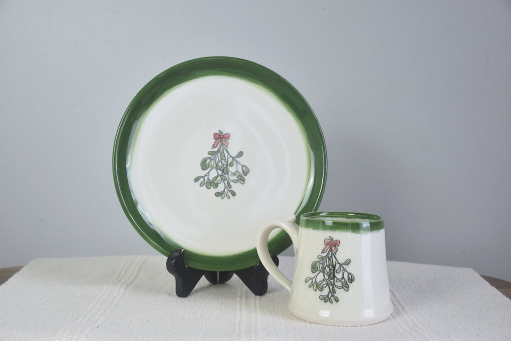 Handmade ceramic Christmas Mug with classic Mistletoe design, red bow, and green rim. 