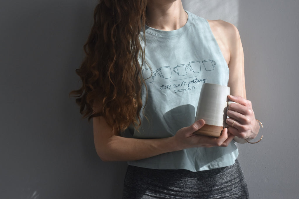 Pale Blue Women's Tank with row of illustrated mugs on it, with "Dirty South Pottery, Winchester, KY" written underneath. Design & photos copyright Dirty South Pottery, LLC 2024