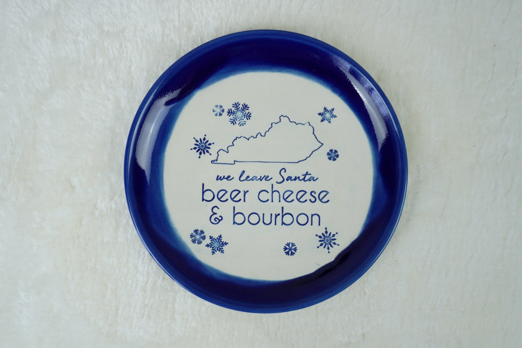 Handmade blue plate with 'we leave Santa beer cheese and bourbon" , the state of Kentucky, and snowflakes stamped into it. Gift for bourbon enthusiast, bourbon gift idea, gift for parents, bourbon decor, Santa plate, Kentucky gift
