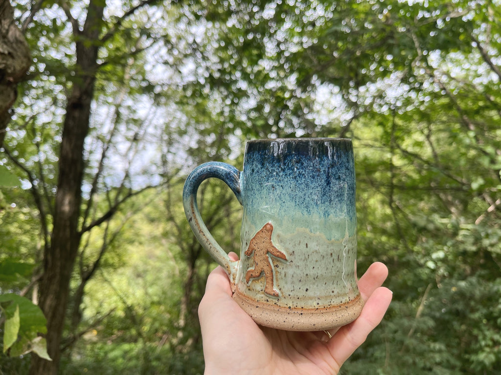 Bigfoot Mug in woods . Handmade mug from Winchester, KY
