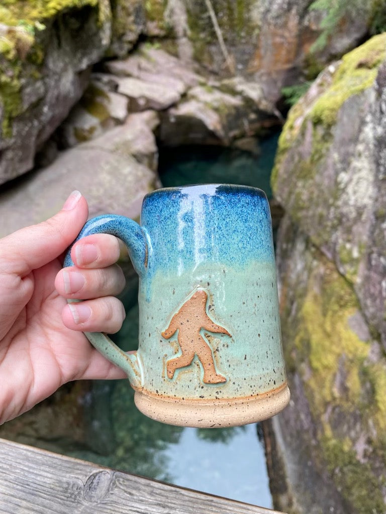 Handmade cryptid mug in front of river